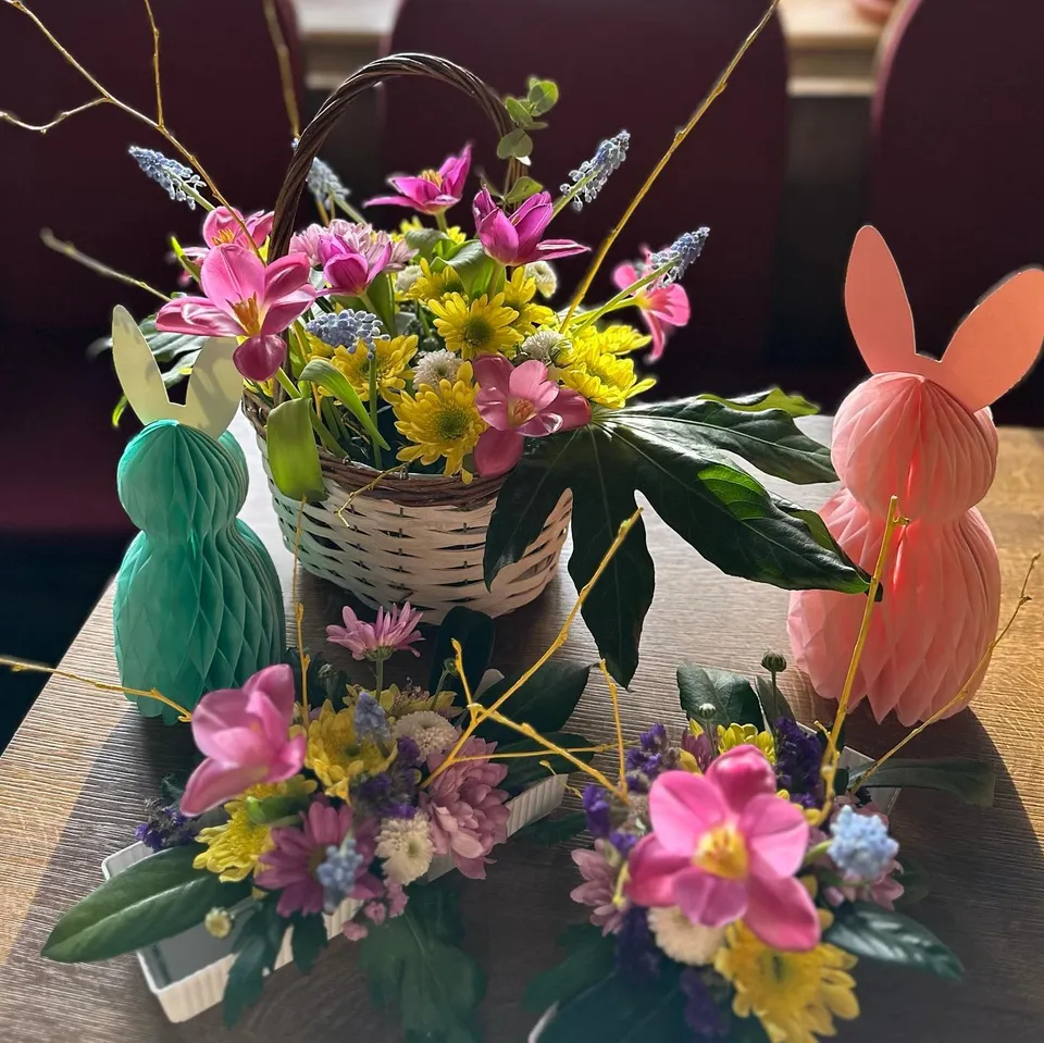 Bunter Frühlingsstrauß mit rosa und gelben Blumen auf einem Tisch im Restaurant