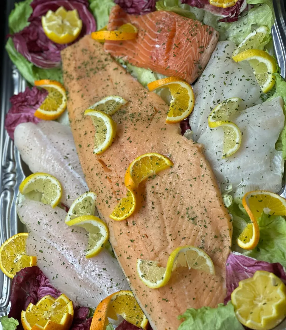 Frische Lachs- und Fischplatte mit Zitronen, angerichtet für das Buffet