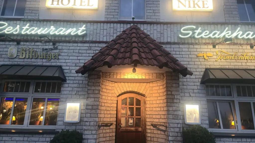 Haus Wessels an der Prosperstraße bei Nacht: beleuchtete Schriftzüge über dem Restaurant-Eingang mit kleinem Ziegeldach