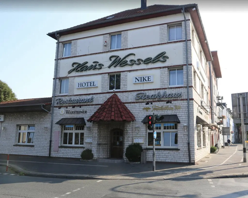 Haus Wessels von der Straßenecke aus, mit Restaurant-Eingang und Parkplatz an der Seite